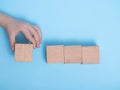 Hand placing wooden block on a blue background. A child`s hand holds a cube. Space for your text Royalty Free Stock Photo