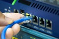 Close-up of a hand plugging a blue ethernet cable into a network switch or router. Concept data connection, internet technology, Royalty Free Stock Photo