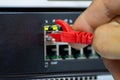 Close-up of a hand plugging a red ethernet cable into a network switch or router Royalty Free Stock Photo