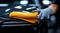 Close-up of hand polishing car surface with yellow cloth Royalty Free Stock Photo