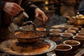 Close-up of a hand pouring coffee from an ornate pot into bowls during a cultural ceremony
