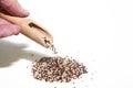 Close-up of a hand pouring quinoa with a wooden spoon into a pile of quinoa