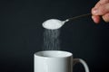 Close up of hand pouring white sugar from spoon to white coffee cup, mug Royalty Free Stock Photo