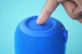 Close-up of a hand pressing a button on a portable blue speaker Royalty Free Stock Photo