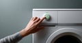 Close-up of hand pressing eco mode button on modern white washing machine with gray background Royalty Free Stock Photo