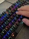 close up of a hand pressing the keys of a gaming computer keyboard, with backlit black keys changing color,human hand tapping a