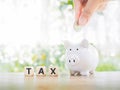 Close up hand putting coin into the piggy bank, The concept of save money for paying tax in the future Royalty Free Stock Photo