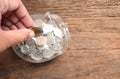 Close up of hand putting coins into clear piggy bank on wooden background. Royalty Free Stock Photo