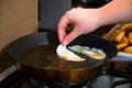 Close up of hand putting gyoza dumplings with mushroom filling into hot frying pan. Golden crunchy dumplings cooking in oil