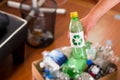 Close up of a hand putting a plastic bottle with a printed sign of recycling in front, inside of a cardboard box full of