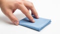 A close up of a hand reaching for a folded blue cloth on a white surface Royalty Free Stock Photo