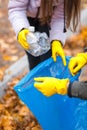 Close-up of a hand in gloves remove a plastic bottle in a garbage bag.