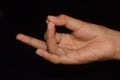 Close up of hand in Rudra Mudra on a black background.