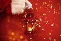 Close up of a hand of Santa Claus in white glove holding a christmas lantern. Red bright background. Copy space Royalty Free Stock Photo