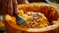 Close-up of hand scooping seeds and pulp from pumpkin with spoon, clean and organized process