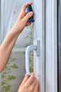 Close-up of hand with screwdriver is dismantling plastic window.