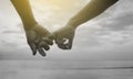 Close up hand of senior couple hook each other's little finger together near seaside at the beach,black and white picture