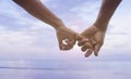 Close up hand of senior couple hook each other's little finger together near seaside at the beach,filtered image