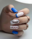 Close-up of a hand showcasing blue and white manicure with abstract lines and star patterns, complemented by stylish Royalty Free Stock Photo
