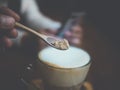 Close up a hand with a spoon pouring sugar in a coffee cup Royalty Free Stock Photo