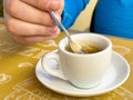 Close-up of hand stirring coffee in white cup on yellow table Royalty Free Stock Photo