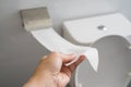 Close up a hand is taking toilet paper with toiler bowl background Royalty Free Stock Photo