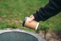 A man throws a paper disposable cup into the trash can in the park. Royalty Free Stock Photo