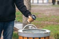 A man throws a paper disposable cup into the trash can in the park. Royalty Free Stock Photo