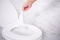 Close up hand throwing toilet paper to the toilet in a white tile bathroom Royalty Free Stock Photo