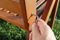 Close-up of a hand tightening a loose screw on a garden chair. Focused on the screw and Allen key.