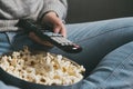 Close-up of hand with TV remote control and popcorn
