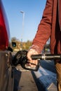 Close up on hand of unknown caucasian man hold black gas pump nozzle pouring gasoline into the fuel tank refueling petroleum to Royalty Free Stock Photo