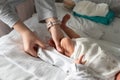 Close up on hand of unknown woman holding leg of her newborn baby - caucasian mother dressing or undressing her little baby on the Royalty Free Stock Photo