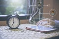 Close up hand using computer tablet with Alarm clock on table beside window Royalty Free Stock Photo