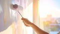 Close-up of hand using paint roller on wall with sunlit background painting Royalty Free Stock Photo