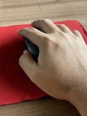 hand using red mouse on a black background with a wooden table Royalty Free Stock Photo