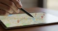 A close-up of a hand using a stylus on a tablet screen, displaying a digital map. The map Royalty Free Stock Photo