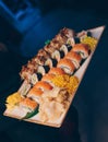 Close-up Hand Waiter holding Set Delicious fresh Sushi slate plate, Japanese raw fish in traditional restaurant. Philadelphia