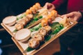 Close-up Hand Waiter holding Set Delicious fresh Sushi slate plate, Japanese raw fish Warm Ebi Sake Unagi . Philadelphia flesh