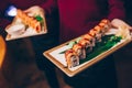 Close-up Hand Waiter holding Set Delicious fresh Sushi slate plate Sushi Rolls Warm Sake Unagi, Japanese raw fish in traditional