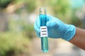 Close up hand wear blue glove, holds test tube of Copper Sulfate liquid with chemical formula CuSO4