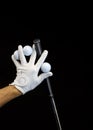 Close up of a hand wearing a golf glove holding some golf balls and a golf club between the fingers Royalty Free Stock Photo