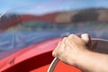 Close up from a hand on a wheel of a motorboat, blue lake background