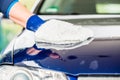 Close-up of hand wiping car with microfiber wash mitt