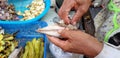 Close up hand of woman or chef taking the fish bone out of mackerel with garlic grilled and green pepper at local street food. Royalty Free Stock Photo