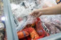 Close up of hand woman chooses packed frozen seafood in freezer in food department of supermarket,asian people panic buying,