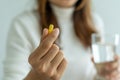 Close up of hand of woman holding a dietary supplement or medication or vitamin and a glass of water ready to take.