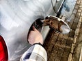 Close up of hand of woman holding gas gun while refueling car with gasoline. Filling fuel into tank of auto at gas Royalty Free Stock Photo