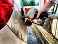 Close up of hand of woman holding gas gun while refueling car with gasoline. Filling fuel into tank of auto at gas Royalty Free Stock Photo