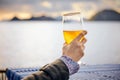 Close up hand of a woman holding a glass of beer with blurred sea, sky and island background Royalty Free Stock Photo